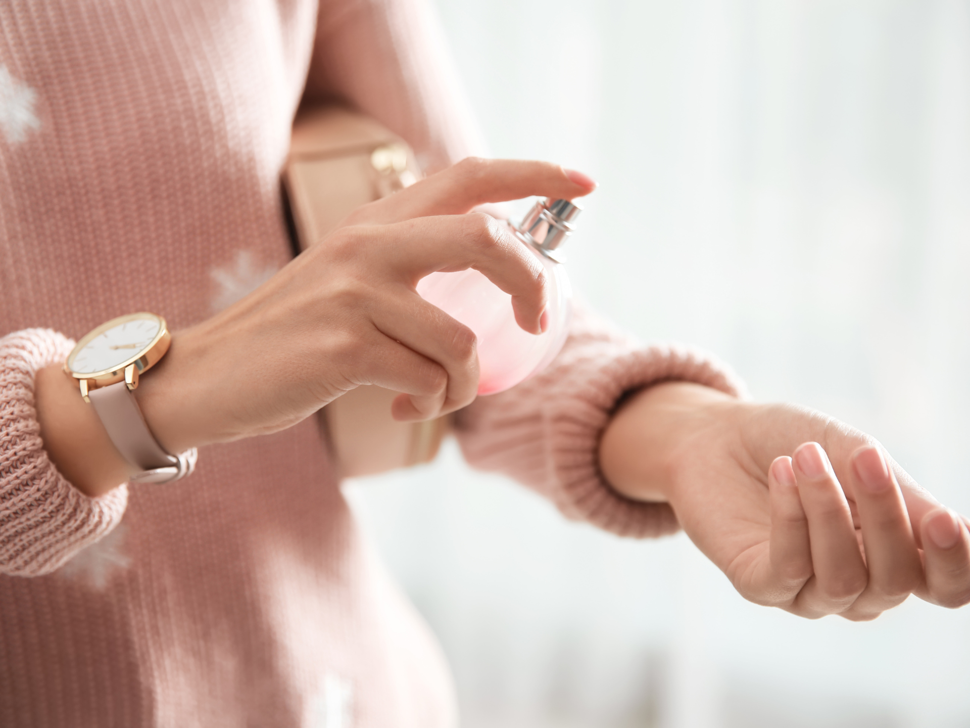 kobieta psikająca rękę perfumami